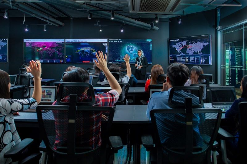 APU students in computer lab raising their hands.
